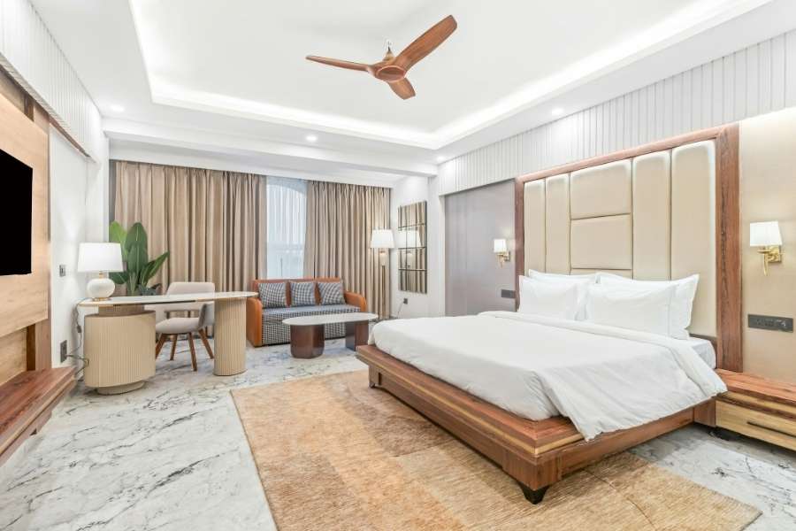 A luxurious hotel bedroom showcasing a contemporary interior design style with warm wood tones and marble floors.