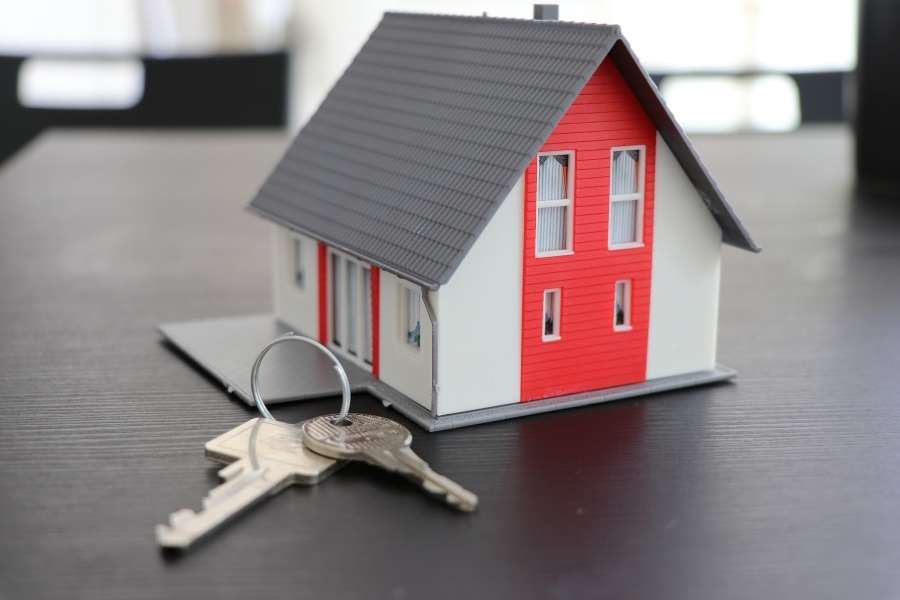 A miniature house model displayed next to a set of keys to represent a rental property.