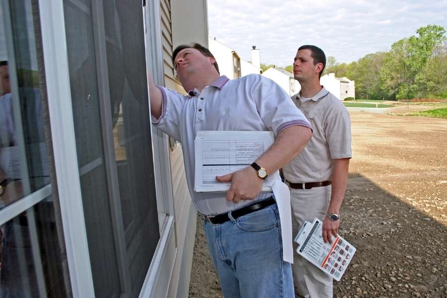 A home inspector checking a window screen during a property assessment.